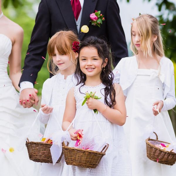 Wedding couple bride and groom with flower children or bridesmaid in white dress and flower baskets